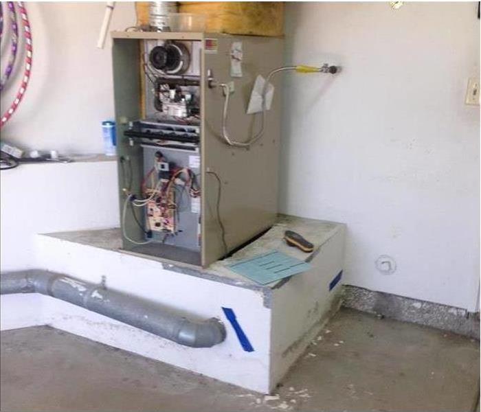 Water heater with mold damage on the stand in garage.