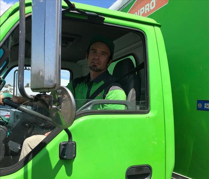 A man driving a big green truck.