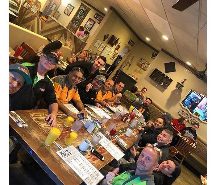 Men and women sitting at a large table eating breakfast.