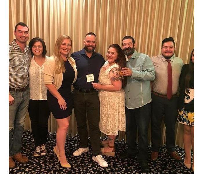 A group of men and women gathered together for a photo at an event.