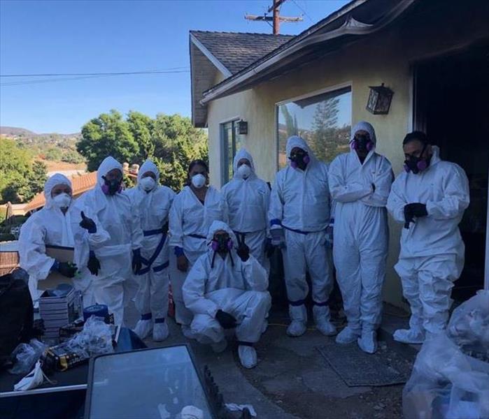 Team memebers suited in white personal protective equipment as house fire.