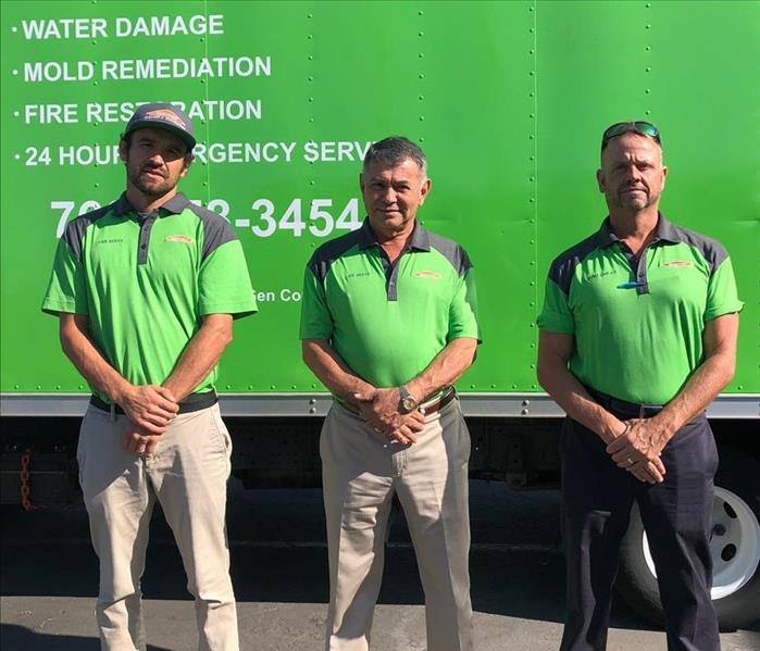 Three owners standing in front of green truck.